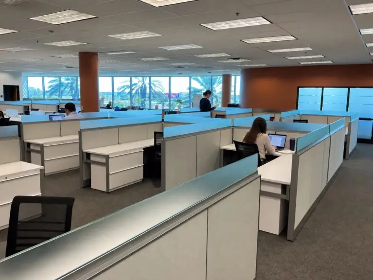 Preowned Knoll cubicles with frosted glass and storage beside office windows; illustrative people added